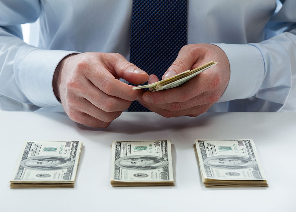20935089 – bank teller’s hands counting dollar banknotes on the table